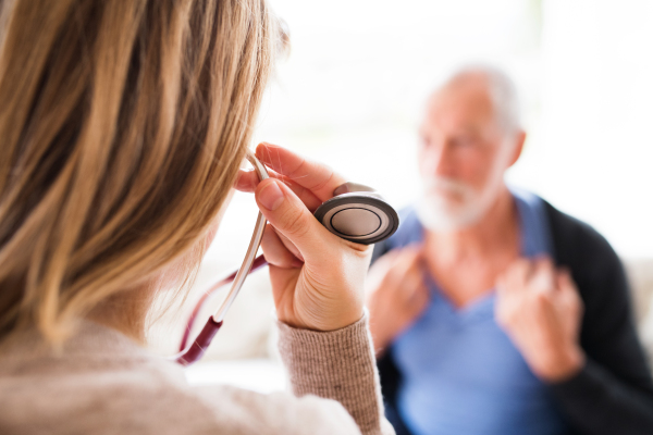 Health visitor and a senior man during home visit. A female nurse or a doctor going to examine a man.