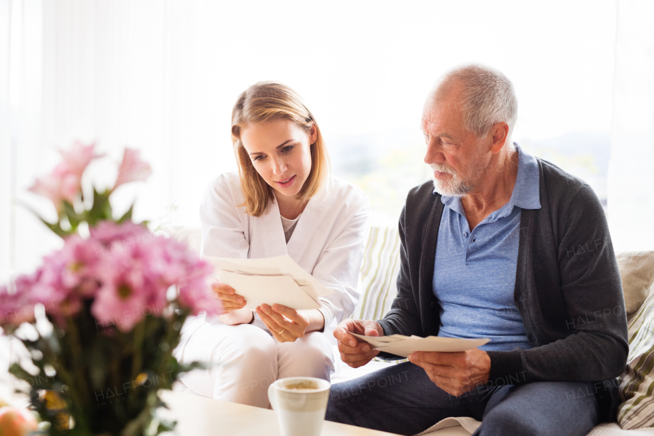 Health visitor and a senior man during home visit. A female nurse or a doctor discussing test results.