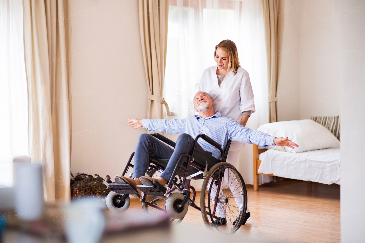 Health visitor or a nurse and a senior man in a wheelchair during home visit.