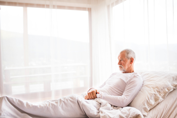 Senior man lying in adjustable bed at home.