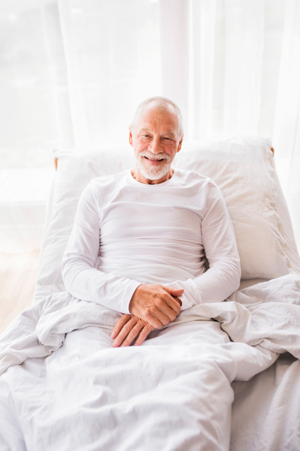 Senior man lying in adjustable bed at home.