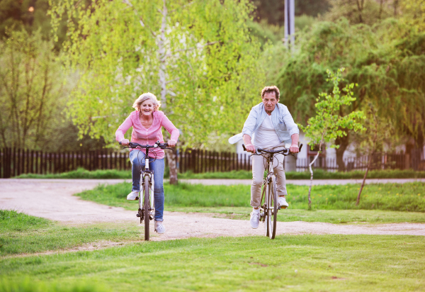 Beautiful senior couple with bicycles outside in spring nature cycling.