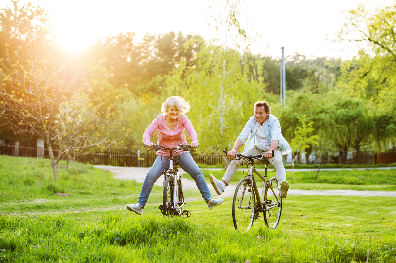 Beautiful senior couple with bicycles cycling outside in spring nature, having fun.