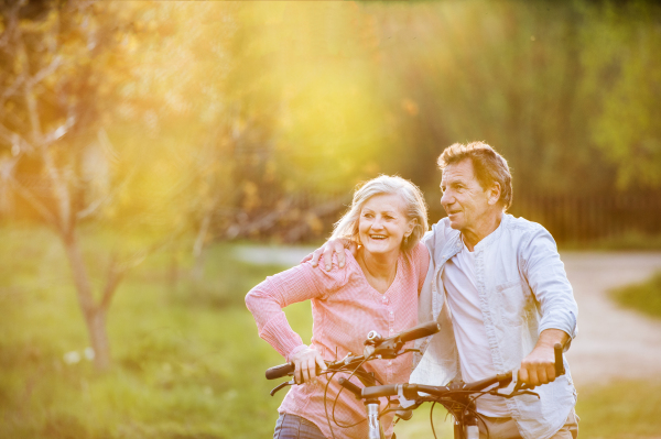 Beautiful senior couple with bicycles outside in spring nature. A man and woman in love.