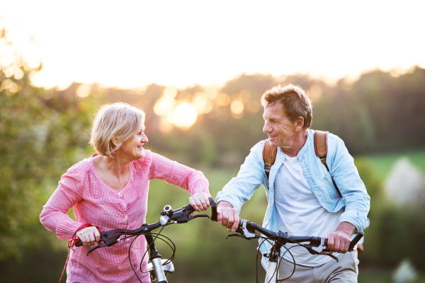 Beautiful senior couple with bicycles outside in spring nature cycling.