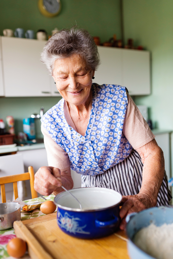 Senior woman baking pies in her home kitchen. Measuring ingredients.