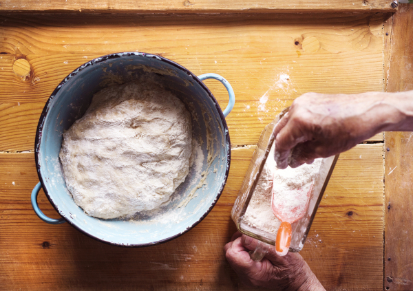 Senior woman baking pies in her home kitchen. Letting yeast dough stand to rise