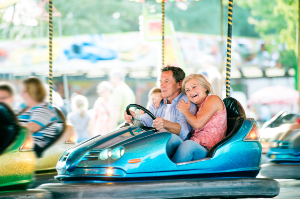 Senior couple having a ride in the bumper car at the fun fair