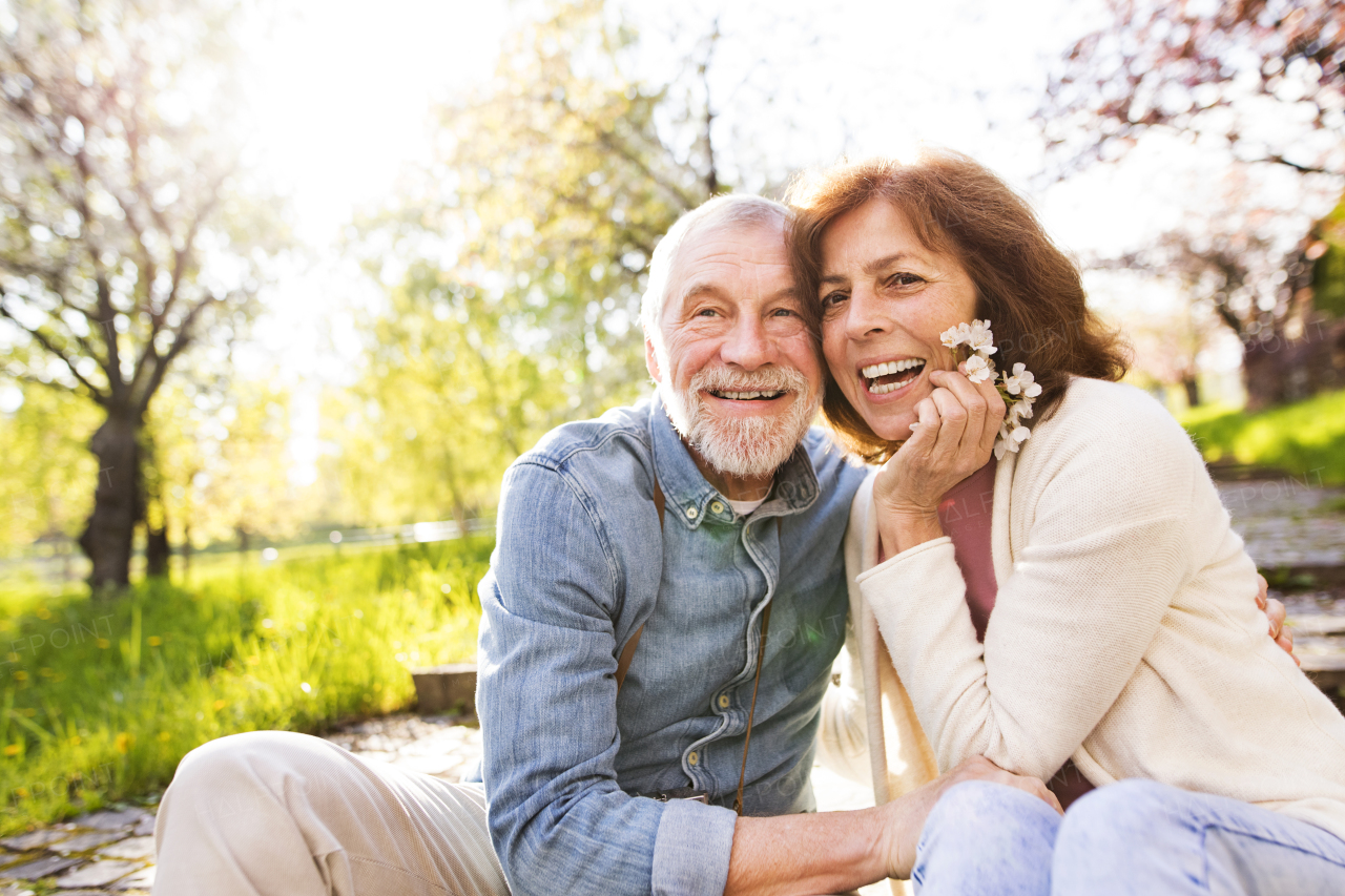 Beautiful senior couple in love outside in spring nature, sitting on stairs, laughing.