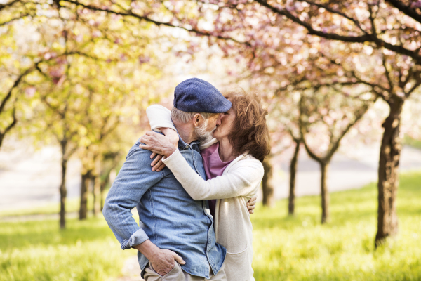 Beautiful senior couple in love kissing outside in spring nature.