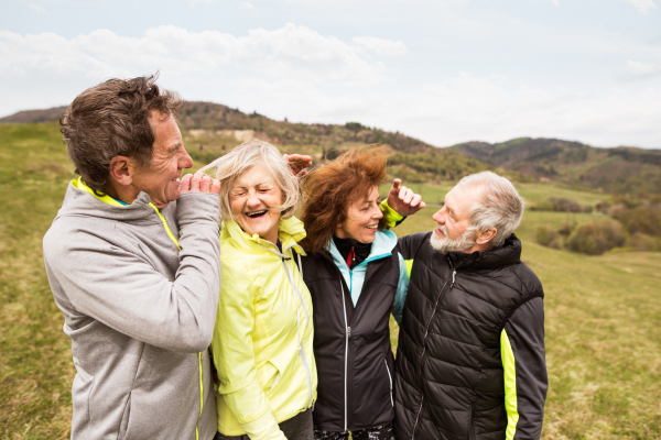 Group of active senior runners outdoors, resting and hugging in windy cold weather.