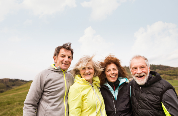 Group of active senior runners outdoors, resting and hugging in windy cold weather.