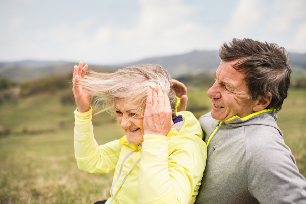 Beautiful active senior runners resting outside in sunny autumn nature, hugging.