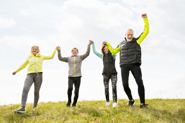 Group of active senior runners outdoors resting, holding hands.