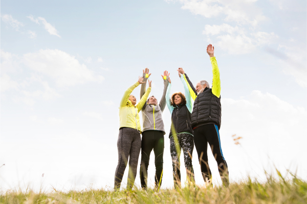 Group of active senior runners outdoors resting, hands in the air.