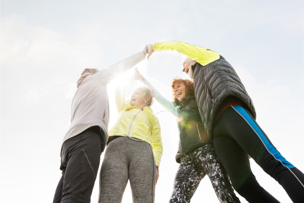 Group of active senior runners outdoors resting, holding hands.