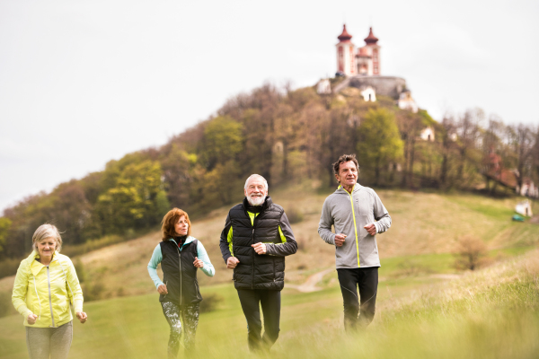 Group of active seniors running together outside on the green hills. Calvary in Banska Stiavnica, Slovakia.