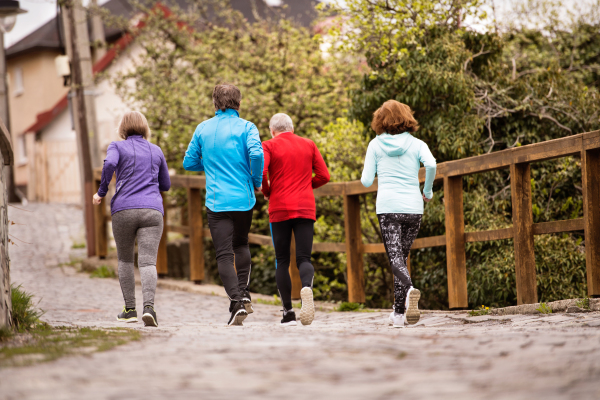 Group of active seniors running together outdoors in the old town of Banska Stiavnica in Slovakia. Rear view.