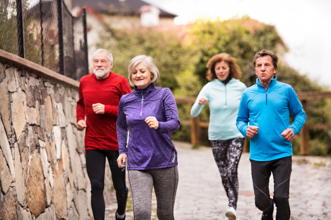 Group of active seniors running together outdoors in the old town of Banska Stiavnica in Slovakia.