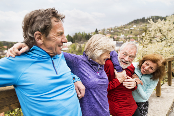 Group of active senior runners posing together outdoors in the old town of Banska Stiavnica in Slovakia.