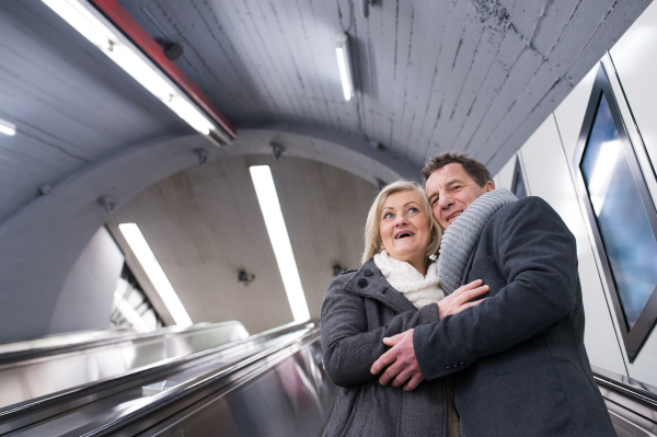 Beautiful senior couple in winter clothes standing at the escalator in Vienna subway