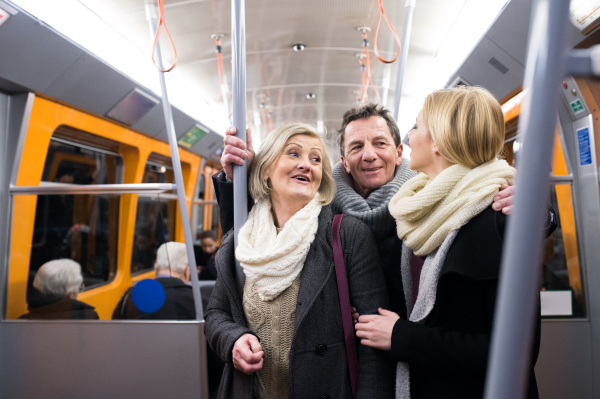 Beautiful senior couple with their daughter in winter clothes traveling by subway train