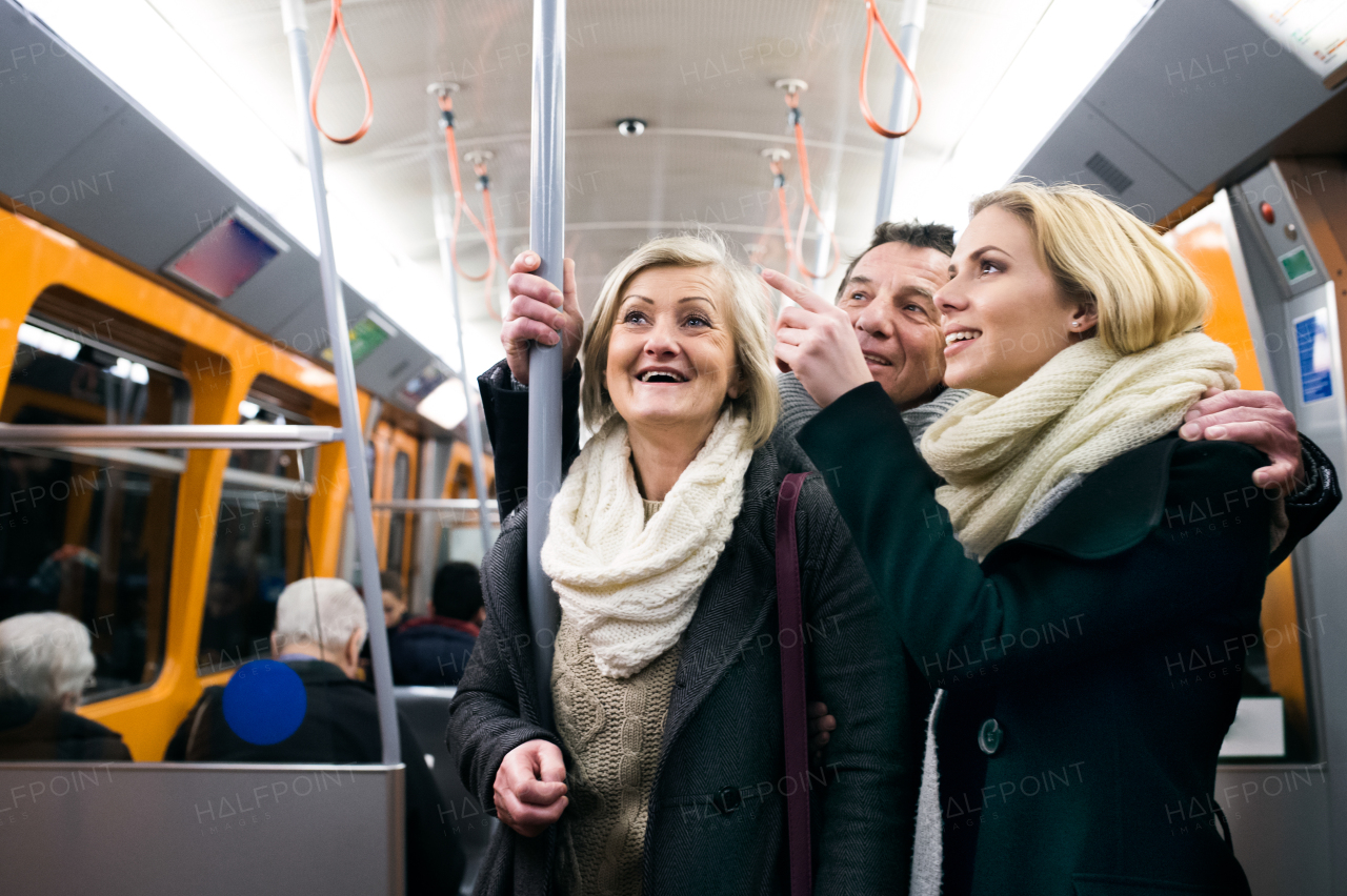 Beautiful senior couple with their daughter in winter clothes traveling by subway train