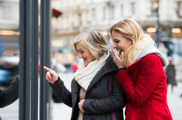 Two beautiful women, mother and daughter, window shopping in historical centre of the city of Vienna, Austria. Winter. Woman pointing at somoething with finger.