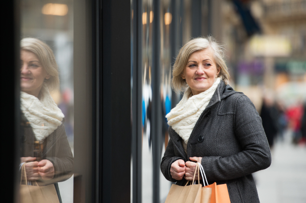 Beautiful senior woman in black coat and woolen scarf window shopping in historical centre of the city of Vienna, Austria. Winter.