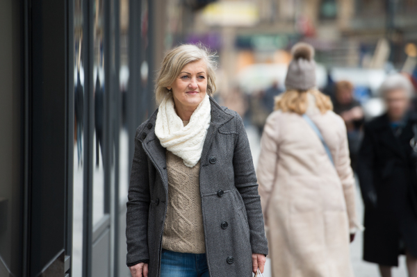 Beautiful senior woman in black coat and woolen scarf on a walk in historical centre of the city of Vienna, Austria. Winter.