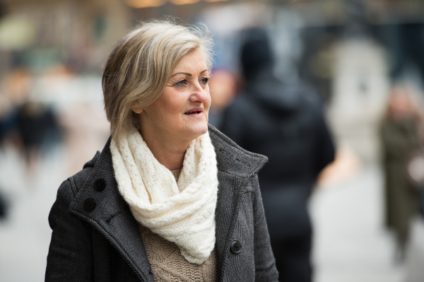 Beautiful senior woman in black coat and woolen scarf on a walk in historical centre of the city of Vienna, Austria. Winter.