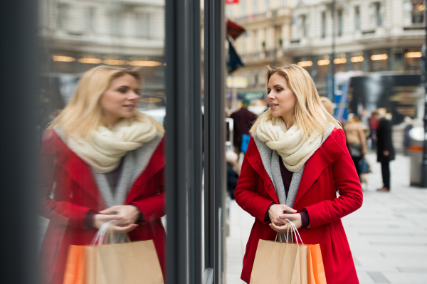 Beautiful young woman in red coat window shopping in historical centre of the city of Vienna, Austria. Winter.