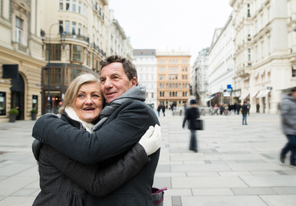 Beautiful senior couple on a walk, hugging in historical centre of the city of Vienna, Austria. Winter.