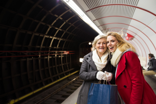 Two beautiful blonde women in winter coats at the underground platform, waiting