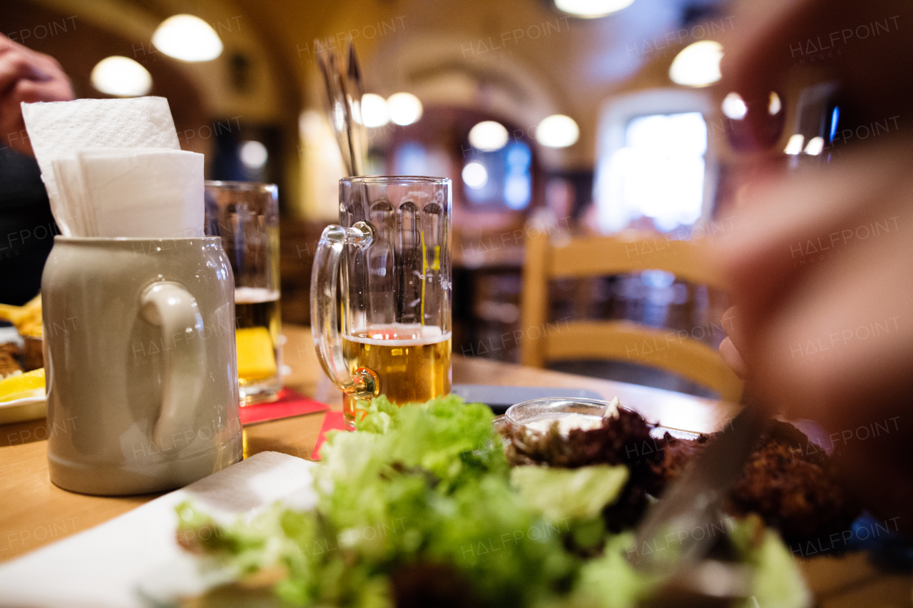 Close up of beer mug and meal laid on wooden table in restaurant.