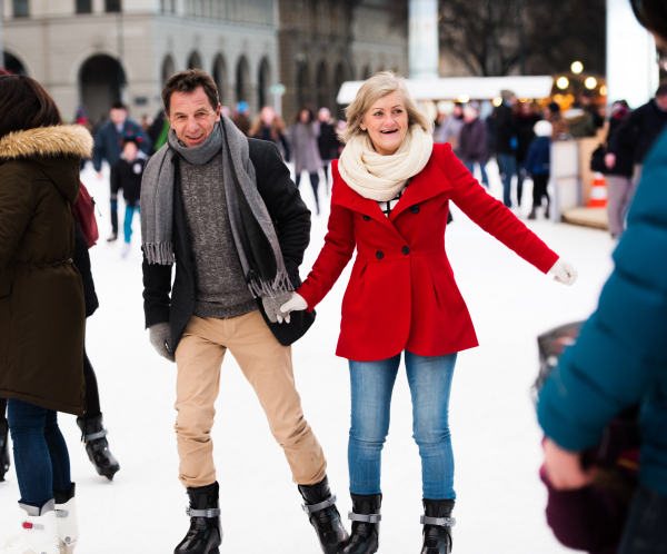 Beautiful senior couple ice skating in the evening in historical centre of the city of Vienna, Austria. Winter.