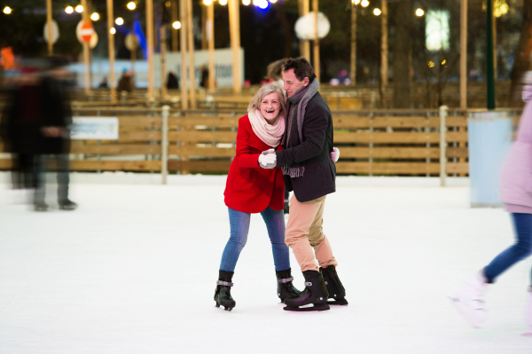 Beautiful senior couple ice skating in the evening in historical centre of the city of Vienna, Austria. Winter.