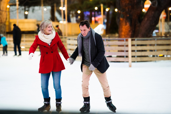 Beautiful senior couple ice skating in the evening in historical centre of the city of Vienna, Austria. Winter.