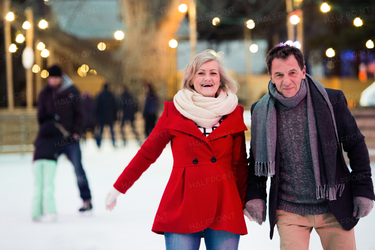 Beautiful senior couple ice skating in the evening in historical centre of the city of Vienna, Austria. Winter.