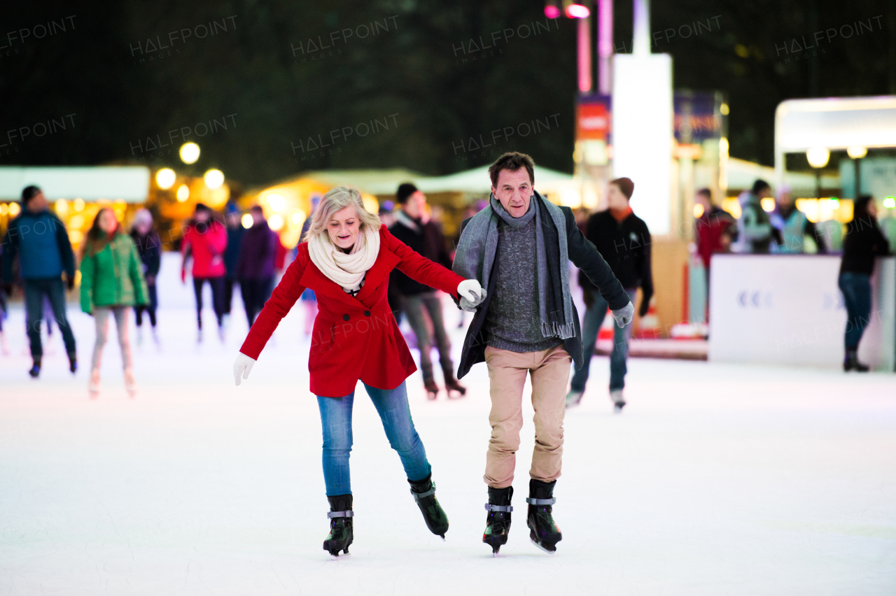 Beautiful senior couple ice skating in the evening in historical centre of the city of Vienna, Austria. Winter.