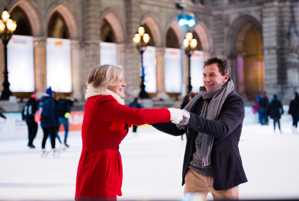 Beautiful senior couple ice skating in the evening in historical centre of the city of Vienna, Austria. Winter.