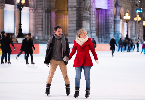 Beautiful senior couple ice skating in the evening in historical centre of the city of Vienna, Austria. Winter.