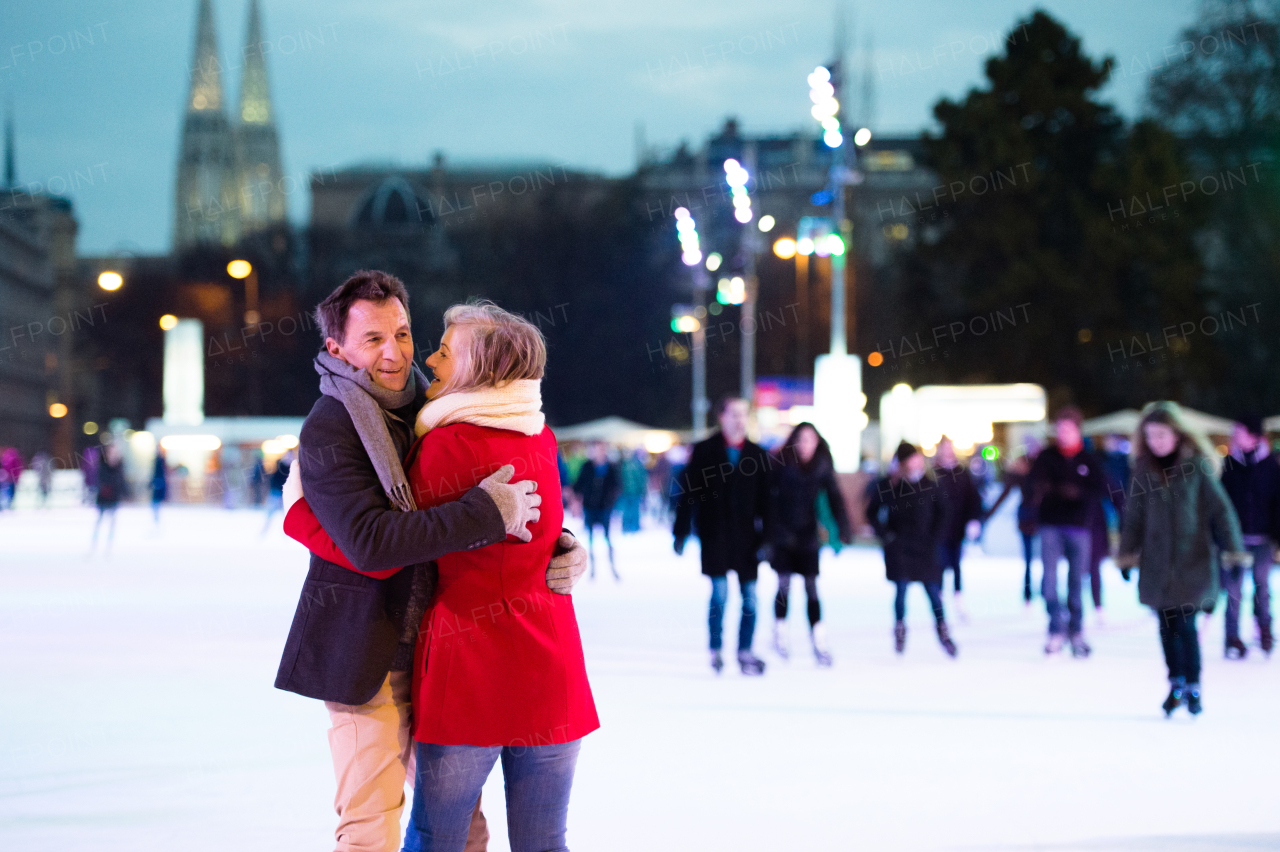 Beautiful senior couple ice skating in the evening in historical centre of the city of Vienna, Austria. Winter.