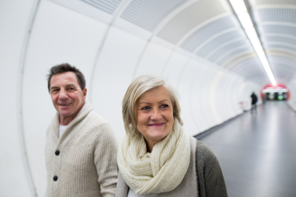 Beautiful senior couple in winter clothes walking in the hallway of subway in Vienna