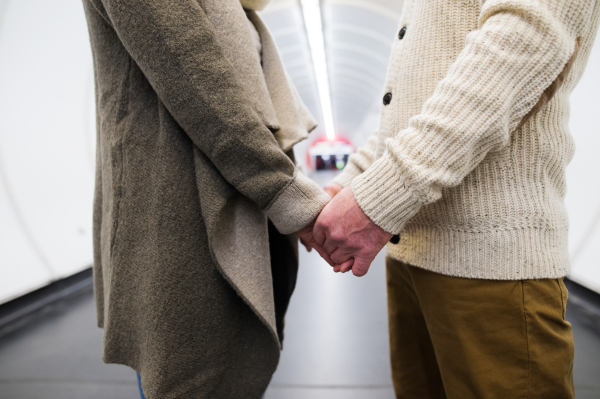 Unrecognizable senior couple in the hallway of subway in Vienna, facing each other, holding hands