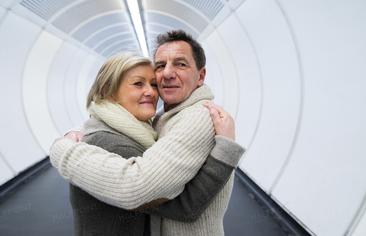 Beautiful senior couple in winter clothes in the hallway of subway in Vienna hugging