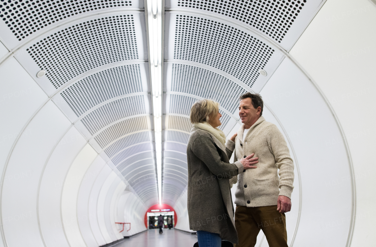 Beautiful senior couple in winter clothes in the hallway of subway in Vienna hugging