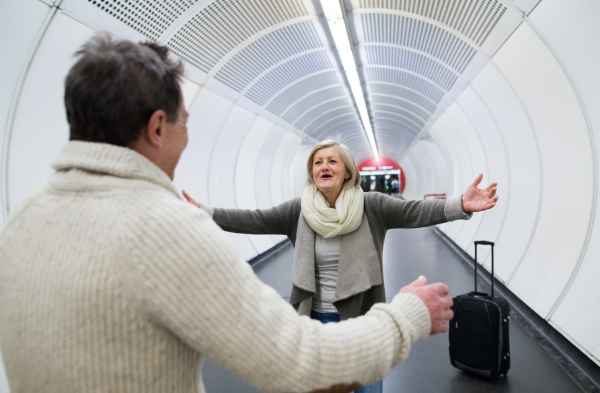 Beautiful senior couple in the hallway of subway in Vienna. Arms open, man wecoming his wife.