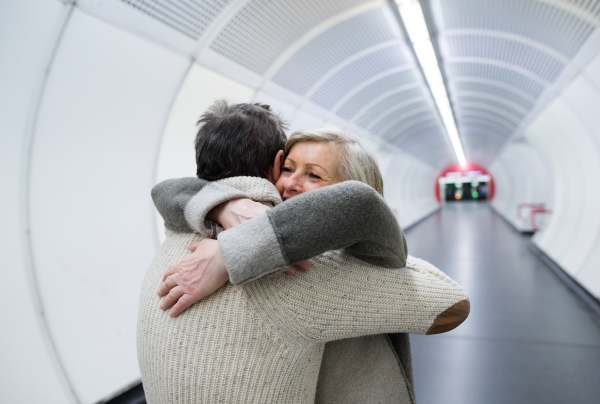 Beautiful senior couple in winter clothes in the hallway of subway in Vienna hugging