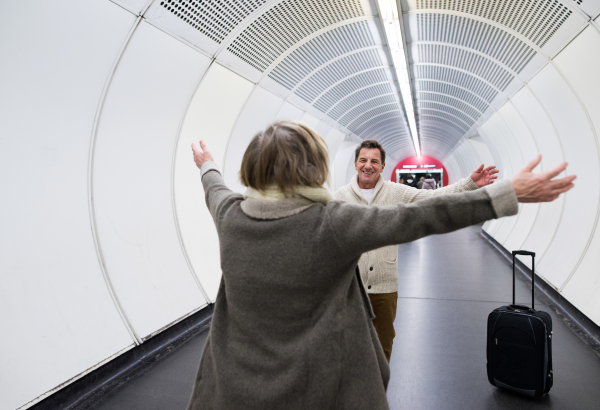 Beautiful senior couple walking in the hallway of subway in Vienna pulling a trolley luggage.